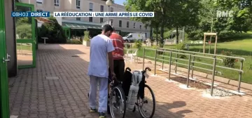 Patient appuyé sur son fauteuil avec son kinésithérapeute faisant des exercices